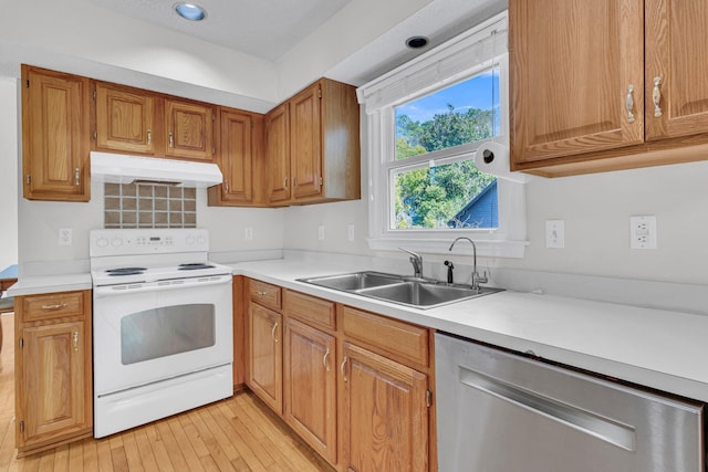 kitchen with electric range, a sink, light countertops, under cabinet range hood, and stainless steel dishwasher