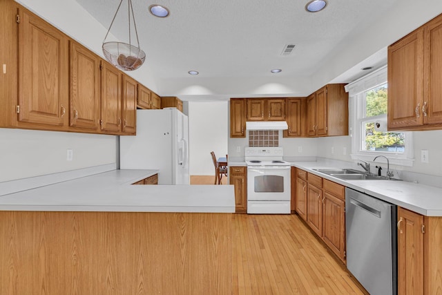 kitchen with white appliances, visible vents, light countertops, under cabinet range hood, and a sink