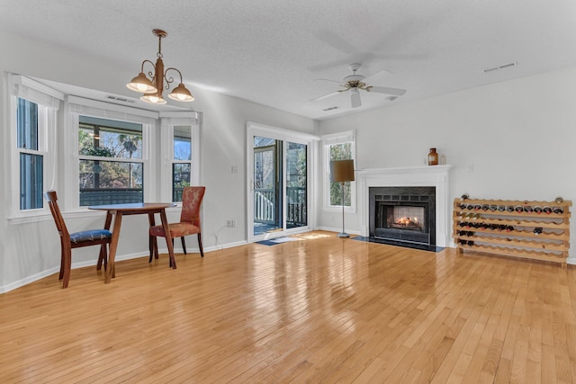 living room with a textured ceiling, light wood finished floors, a fireplace with flush hearth, and baseboards