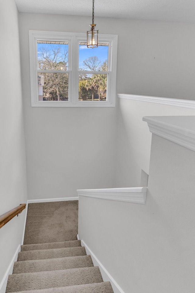 stairs featuring a textured ceiling, carpet, and baseboards