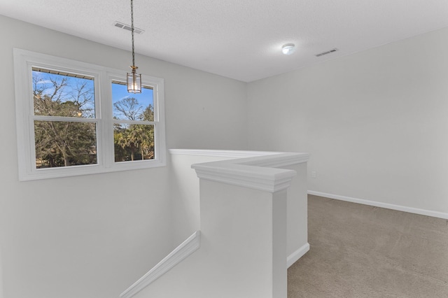 corridor with carpet floors, baseboards, visible vents, and a textured ceiling