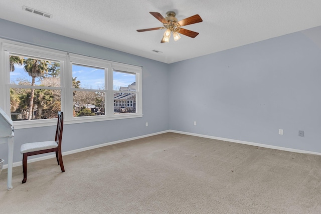 unfurnished office featuring baseboards, visible vents, a textured ceiling, and light colored carpet