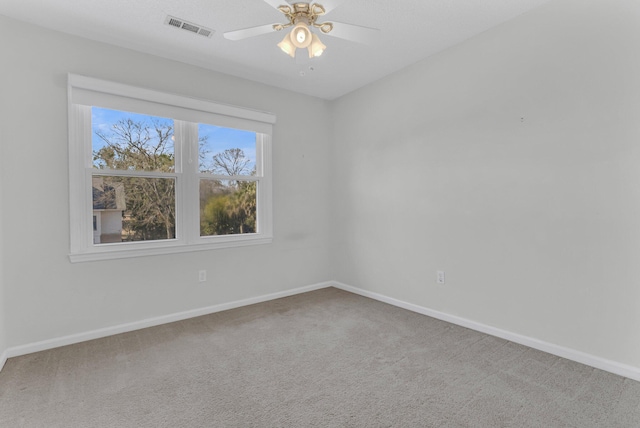 carpeted empty room with a ceiling fan, visible vents, and baseboards