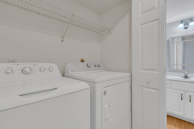 clothes washing area with a sink, laundry area, light wood-style floors, and washer and dryer