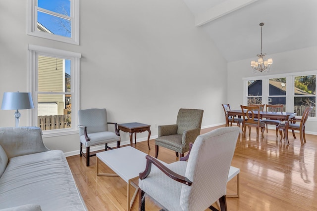 living room featuring high vaulted ceiling, a notable chandelier, light wood-style flooring, and baseboards