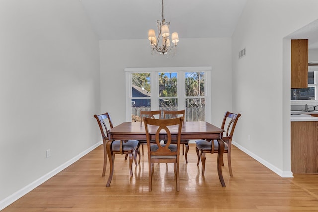 dining area featuring light wood-type flooring, visible vents, baseboards, and a chandelier