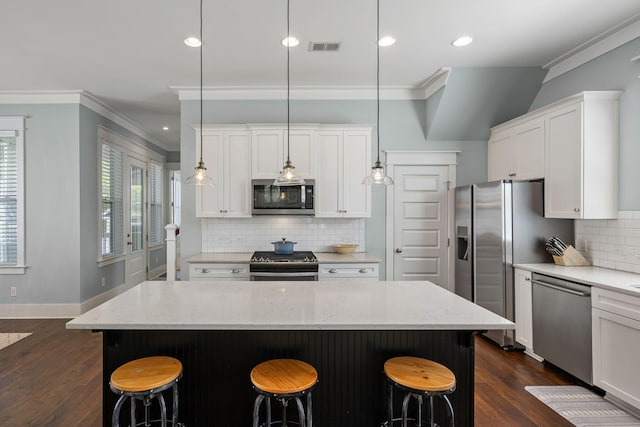 kitchen with a kitchen island, appliances with stainless steel finishes, a breakfast bar, and pendant lighting