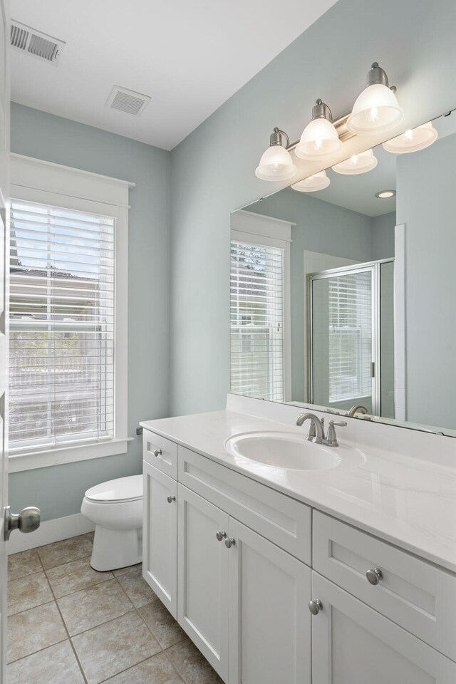 bathroom featuring tile patterned floors, toilet, a shower with door, and vanity