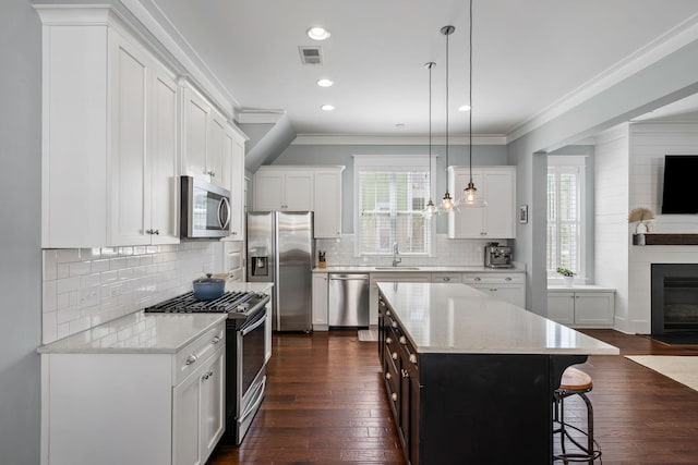 kitchen with hanging light fixtures, stainless steel appliances, a center island, and white cabinets