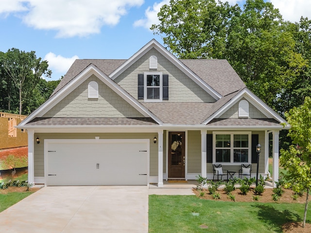 craftsman house with a garage, covered porch, and a front yard