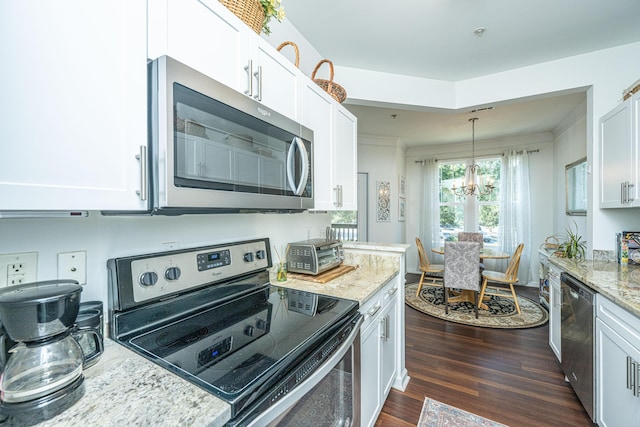 kitchen with pendant lighting, dark wood-type flooring, appliances with stainless steel finishes, light stone countertops, and white cabinets