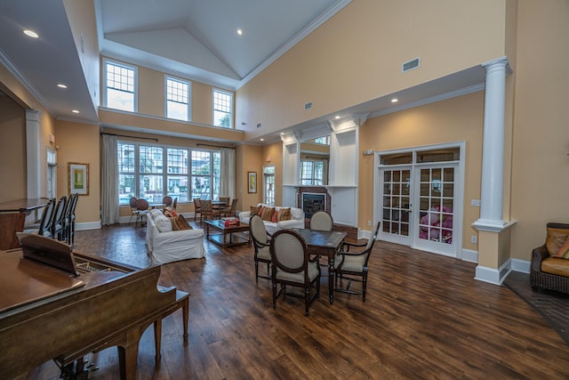 living room with ornate columns, ornamental molding, dark hardwood / wood-style floors, and a towering ceiling