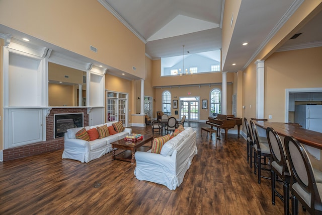 living room featuring crown molding, a fireplace, dark hardwood / wood-style floors, and decorative columns