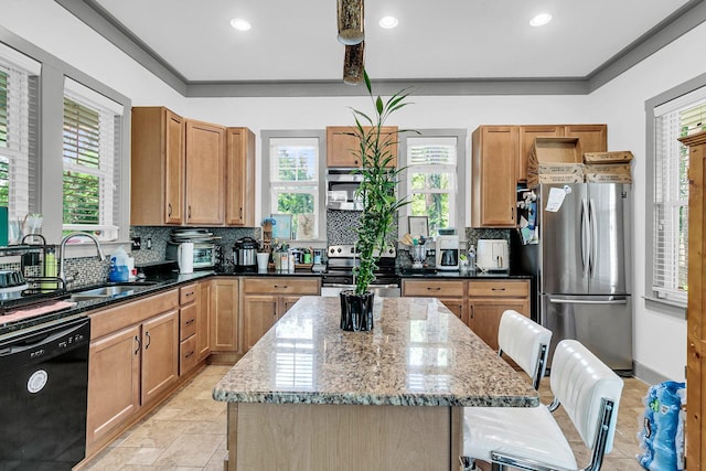 kitchen featuring appliances with stainless steel finishes, light stone counters, a center island, and decorative backsplash