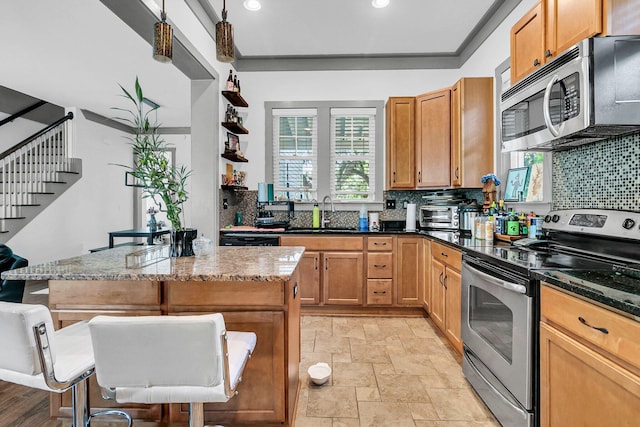 kitchen featuring decorative light fixtures, a kitchen island, sink, decorative backsplash, and appliances with stainless steel finishes