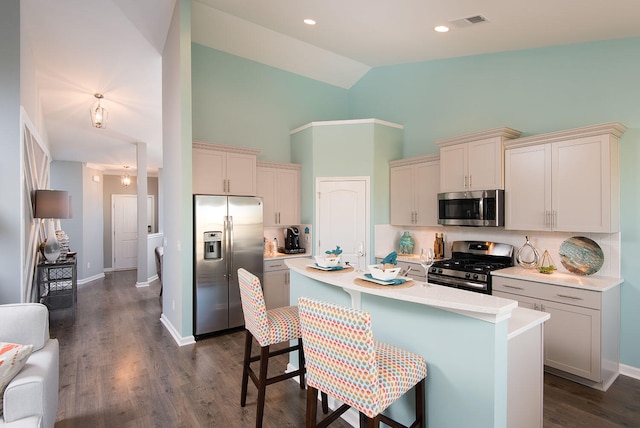 kitchen featuring appliances with stainless steel finishes, a kitchen breakfast bar, high vaulted ceiling, tasteful backsplash, and a center island