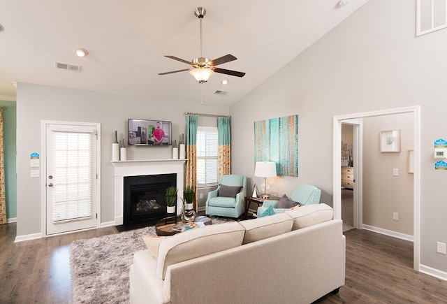 living room with a healthy amount of sunlight, dark wood-type flooring, ceiling fan, and high vaulted ceiling