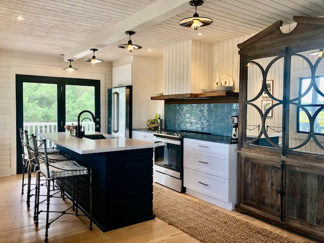 kitchen with light wood finished floors, tasteful backsplash, appliances with stainless steel finishes, beamed ceiling, and a sink