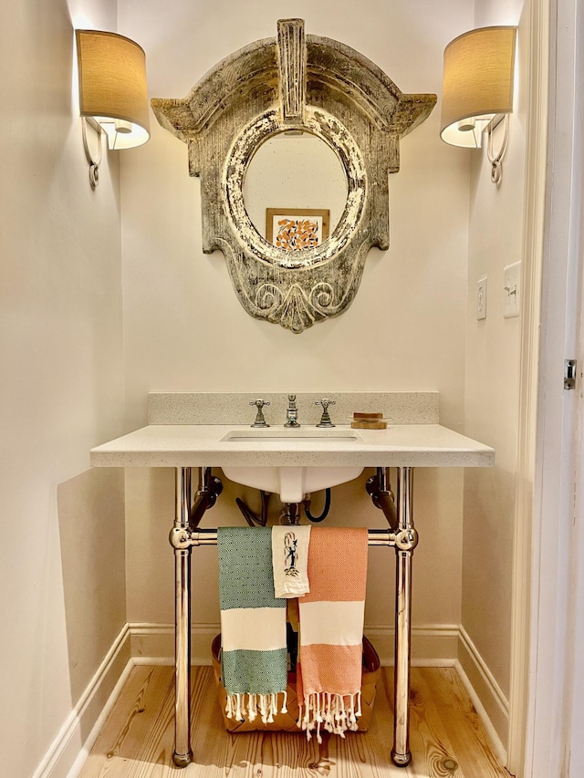 bathroom with a sink, baseboards, and wood finished floors