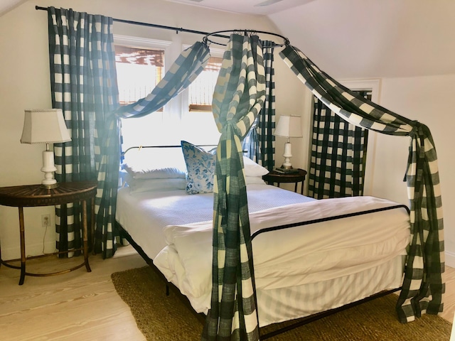 bedroom with lofted ceiling and wood finished floors