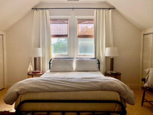 bedroom with visible vents, vaulted ceiling, and wood finished floors