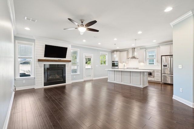 unfurnished living room featuring ceiling fan, dark hardwood / wood-style floors, sink, and crown molding