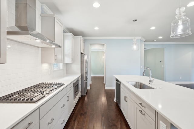 kitchen featuring decorative light fixtures, wall chimney exhaust hood, sink, and white cabinetry