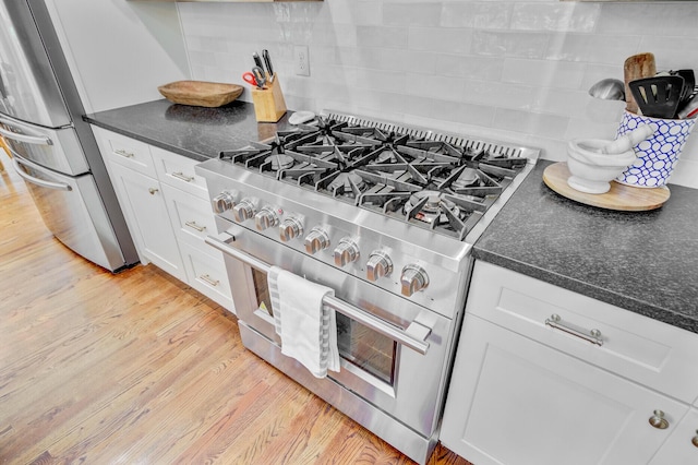 4227 Sawgrass Dr, North Charleston, SC 29420 - kitchen with appliances with stainless steel finishes, backsplash, white cabinets, light wood-style floors, and dark stone countertops