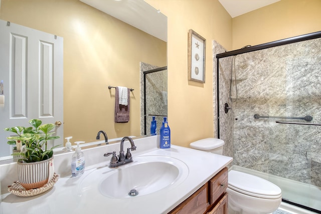 bathroom with a shower with door, vanity, and toilet