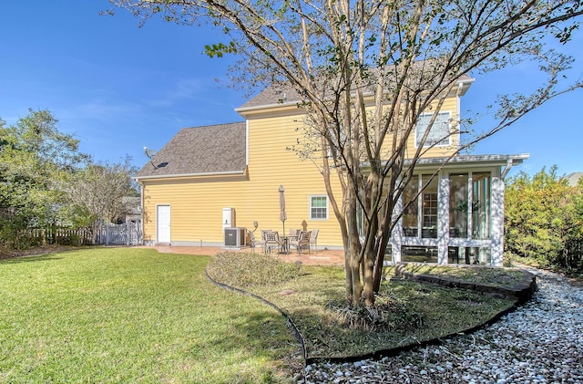 rear view of property with central air condition unit, a sunroom, a yard, and a patio