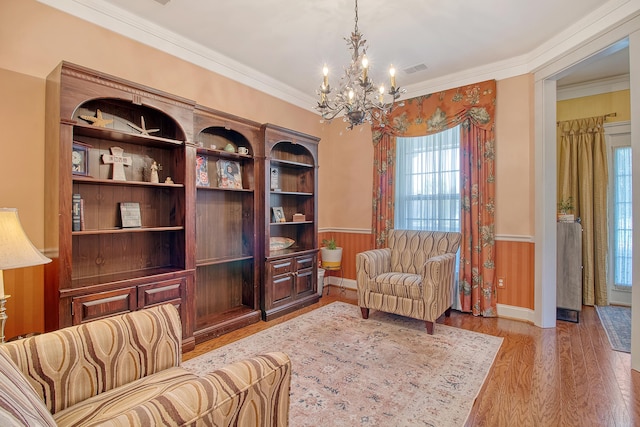 living area featuring a notable chandelier, wood walls, crown molding, and light hardwood / wood-style flooring