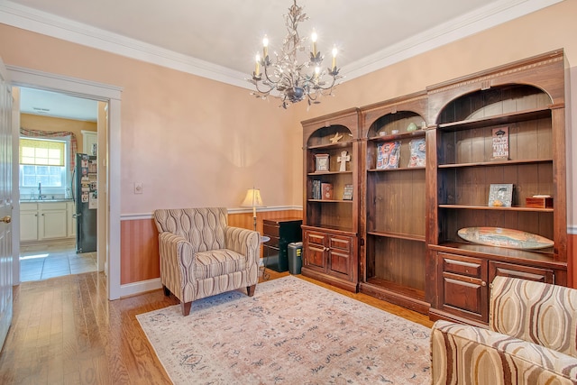 sitting room with light hardwood / wood-style floors, ornamental molding, sink, and a chandelier