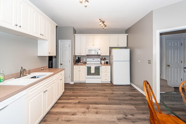 kitchen featuring white cabinets, sink, white appliances, a textured ceiling, and dark hardwood / wood-style flooring