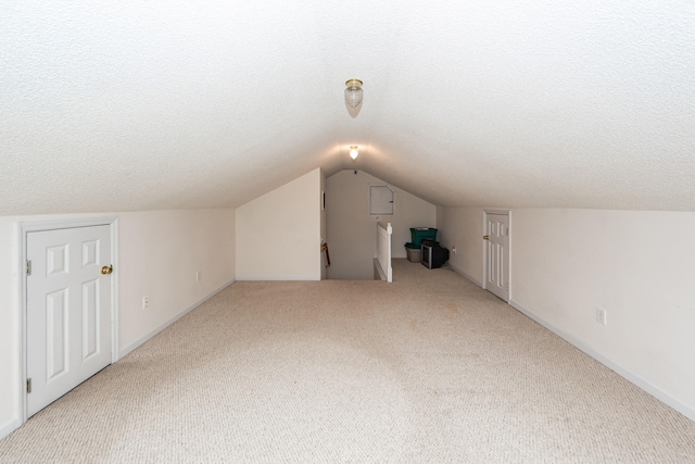 additional living space featuring light carpet, lofted ceiling, and a textured ceiling