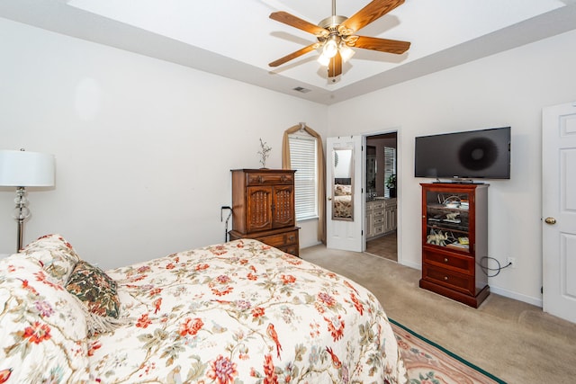 bedroom featuring ceiling fan, light colored carpet, and ensuite bath