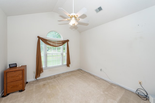 carpeted spare room featuring vaulted ceiling and ceiling fan