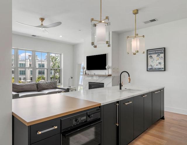 kitchen featuring open floor plan, visible vents, a sink, and black oven