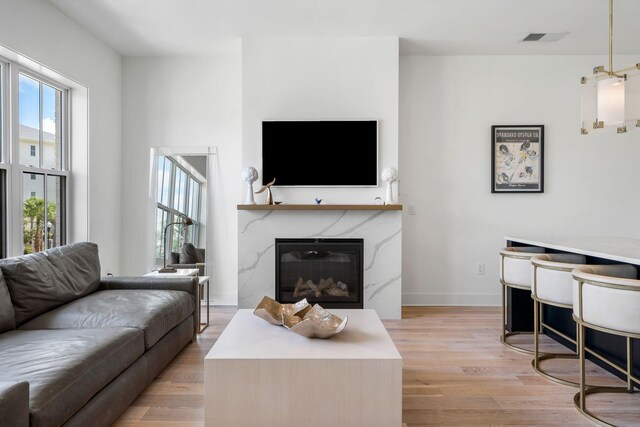 living area with light wood-type flooring, visible vents, plenty of natural light, and a fireplace