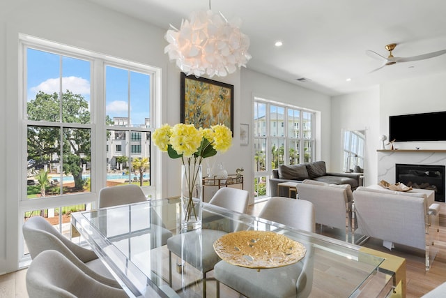 dining room with recessed lighting, visible vents, a premium fireplace, light wood-style floors, and ceiling fan with notable chandelier