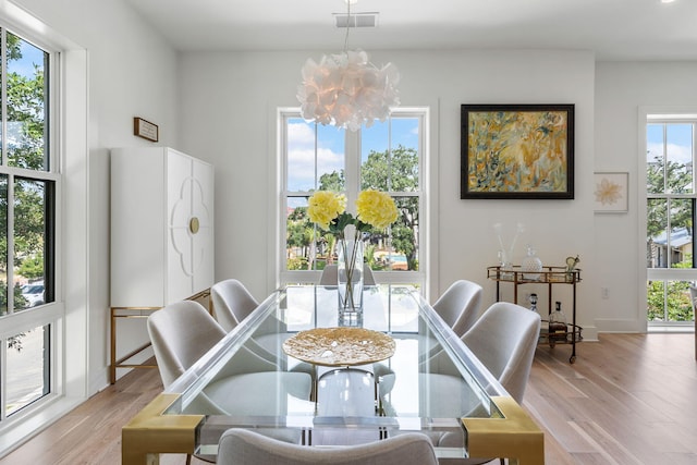 dining space featuring light wood-style flooring, visible vents, a chandelier, and baseboards