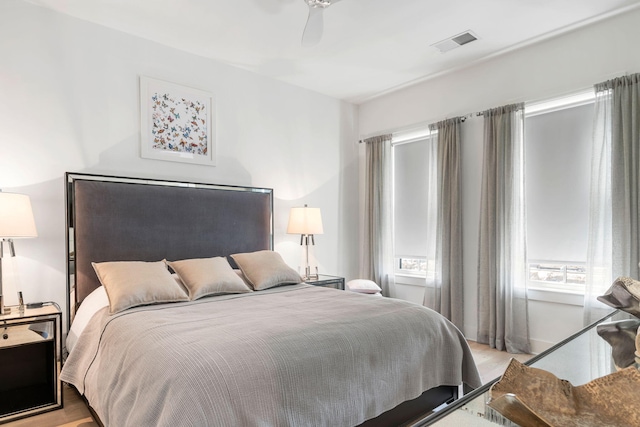 bedroom featuring a ceiling fan, visible vents, and wood finished floors