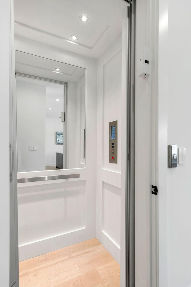 hall featuring recessed lighting, light wood-type flooring, and elevator