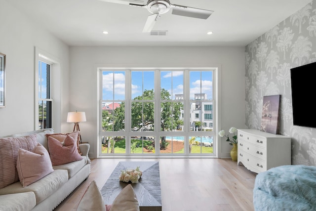 living room with light wood-type flooring, wallpapered walls, visible vents, and recessed lighting