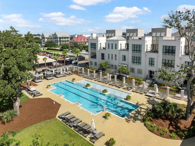 community pool with a residential view, fence, and a patio