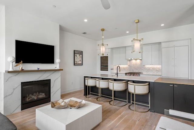 living room with light wood-type flooring, recessed lighting, visible vents, and a high end fireplace