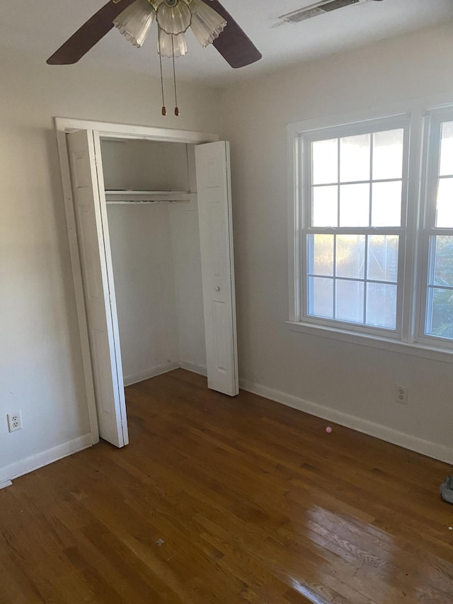 unfurnished bedroom featuring dark wood-type flooring, a closet, and ceiling fan