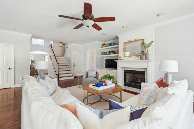 living area with stairs, a fireplace with flush hearth, wood finished floors, and crown molding