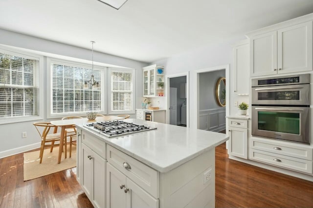 kitchen featuring stainless steel appliances, light countertops, hanging light fixtures, glass insert cabinets, and white cabinets