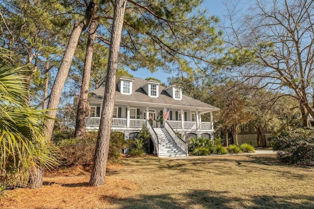 view of front facade with a porch, a front yard, and stairway