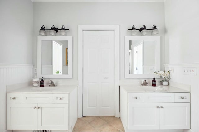 bathroom with a wainscoted wall, a closet, tile patterned flooring, and a sink